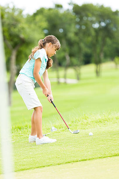 istock Little girl putts ball at golf course 509993968