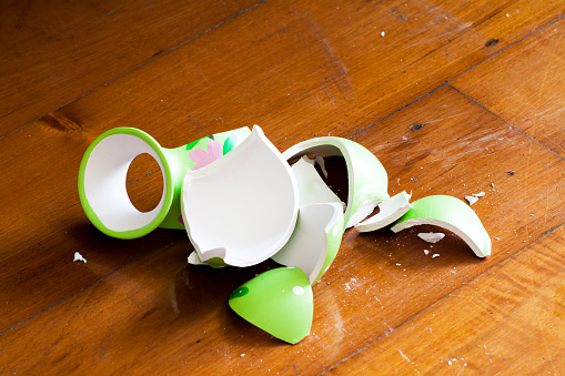 green broken vase on wooden floor