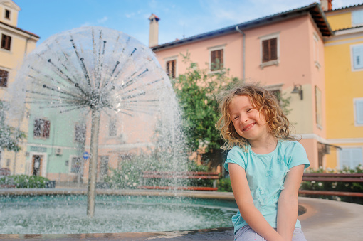 child girl relaxing at fountain in Izola (Isola) city in Slovenia. Traveling in Europe on summer vacationchild girl relaxing at fountain in Izola (Isola) city in Slovenia. Traveling in Europe on summer vacation