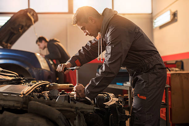 Auto mechanic working on a car engine in repair shop.