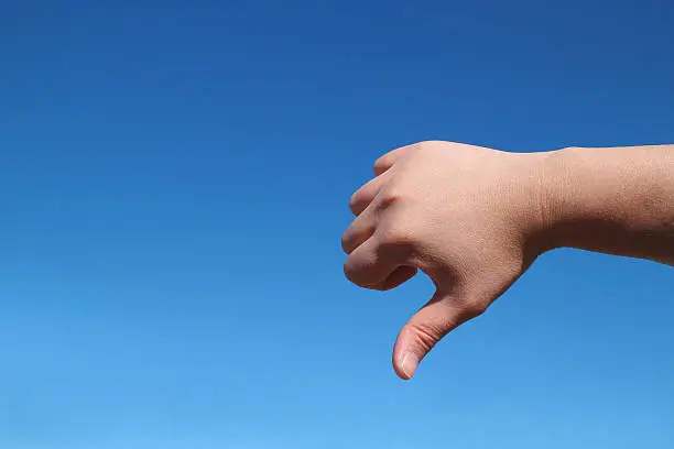 Photo of male hand bad gesture in the blue sky