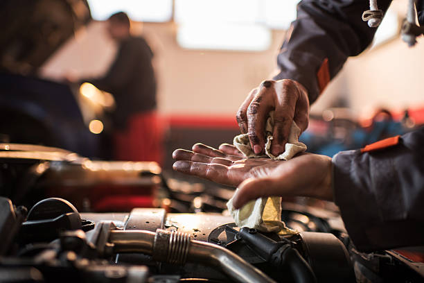 Unrecognizable auto mechanic cleaning his dirty hands. Unrecognizable auto mechanic cleaning dirty hands with a napkin. auto mechanic photos stock pictures, royalty-free photos & images