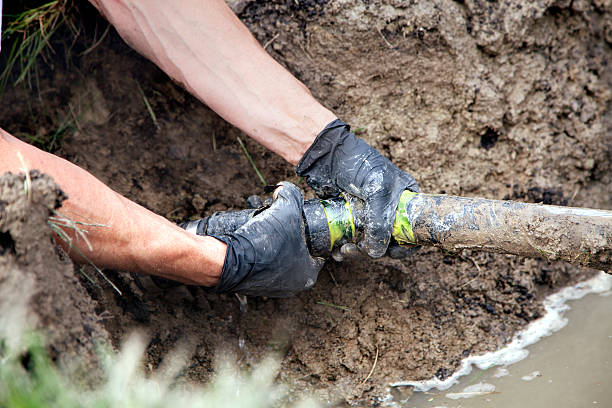 Repairing a Broken Pipe Plumber Repairing a Broken Pipe in a Septic Field drain photos stock pictures, royalty-free photos & images