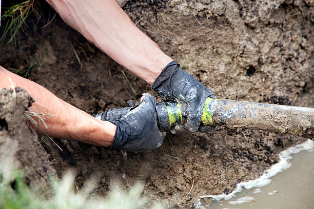 Repairing a Broken Pipe Plumber Repairing a Broken Pipe in a Septic Field laying underground pipes stock pictures, royalty-free photos & images