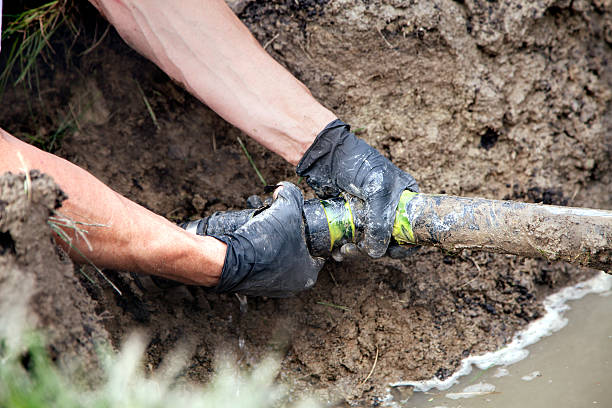 Repairing a Broken Pipe Plumber Repairing a Broken Pipe in a Septic Field sewer drain stock pictures, royalty-free photos & images