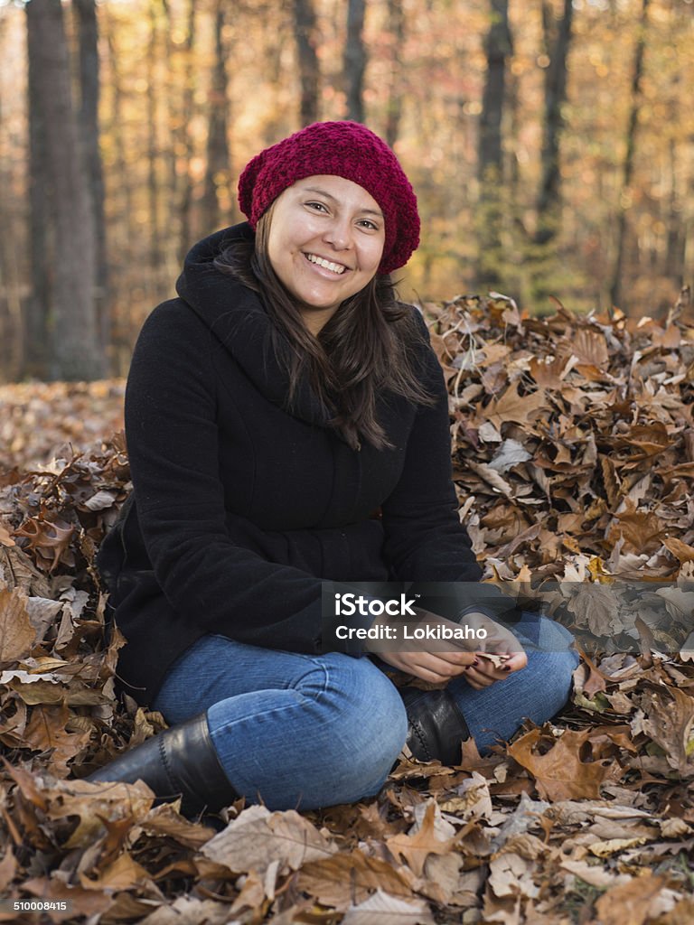 Junge Frau sitzt in einem Haufen Herbstblätter - Lizenzfrei 16-17 Jahre Stock-Foto