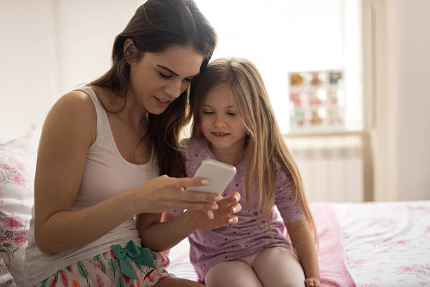 istock Mother and daughter text messaging on cell phone in bedroom. 510008972