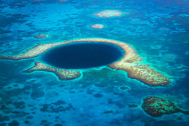 The Blue Hole Lighthouse Reef Belize Aerial View to the famous diving site and natural phenomenon the Blue Hole in the Lighthouse Reef, East of the Turneffe Atoll in Caribbean Sea, Belize, Central America. atoll photos stock pictures, royalty-free photos & images