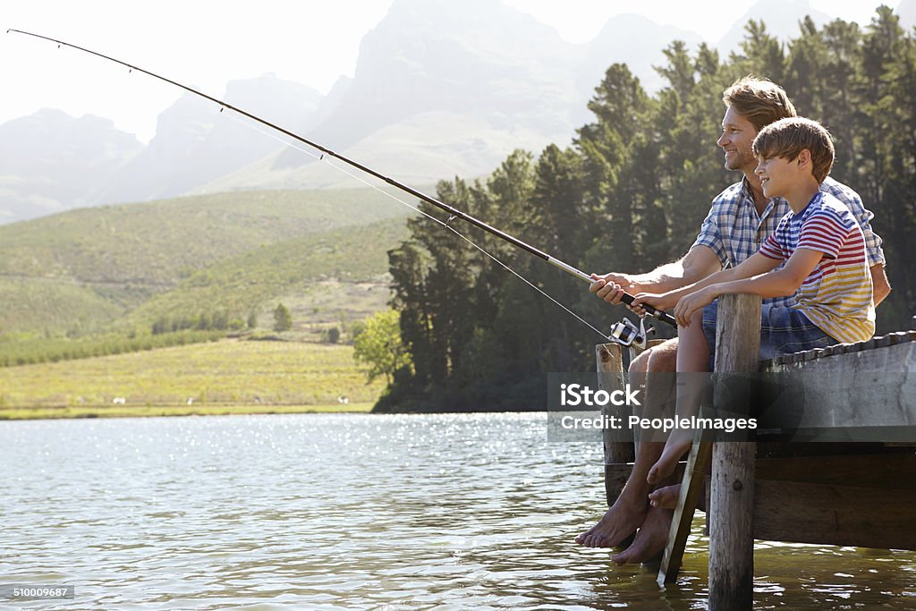 Cast aways! Shot of a father and son sitting on a jetty fishing together Lake Stock Photo