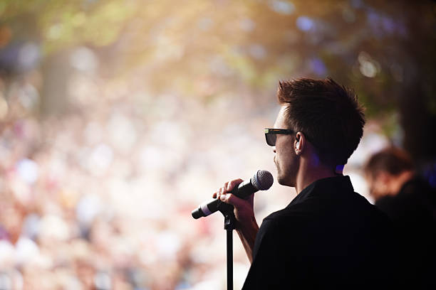 Charismatic frontman A singer performing on stage at an outdoor music festival singer back stock pictures, royalty-free photos & images