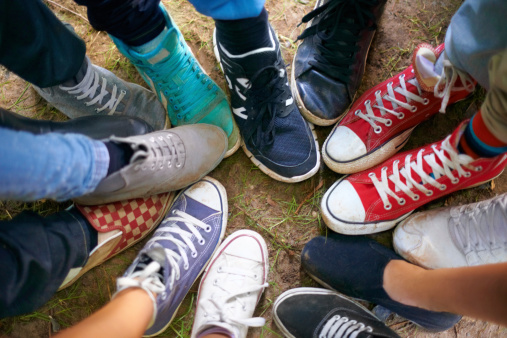 A high-angle view of a group of people wearing sneakers and standing in a circle