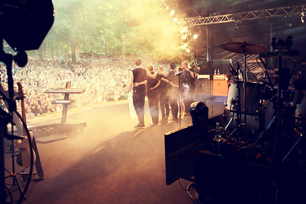 again! A popular band hugging and looking out into the crowd after a successful gig entertainment occupation stock pictures, royalty-free photos & images