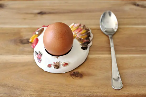 an egg in an egg-holder and a spoon