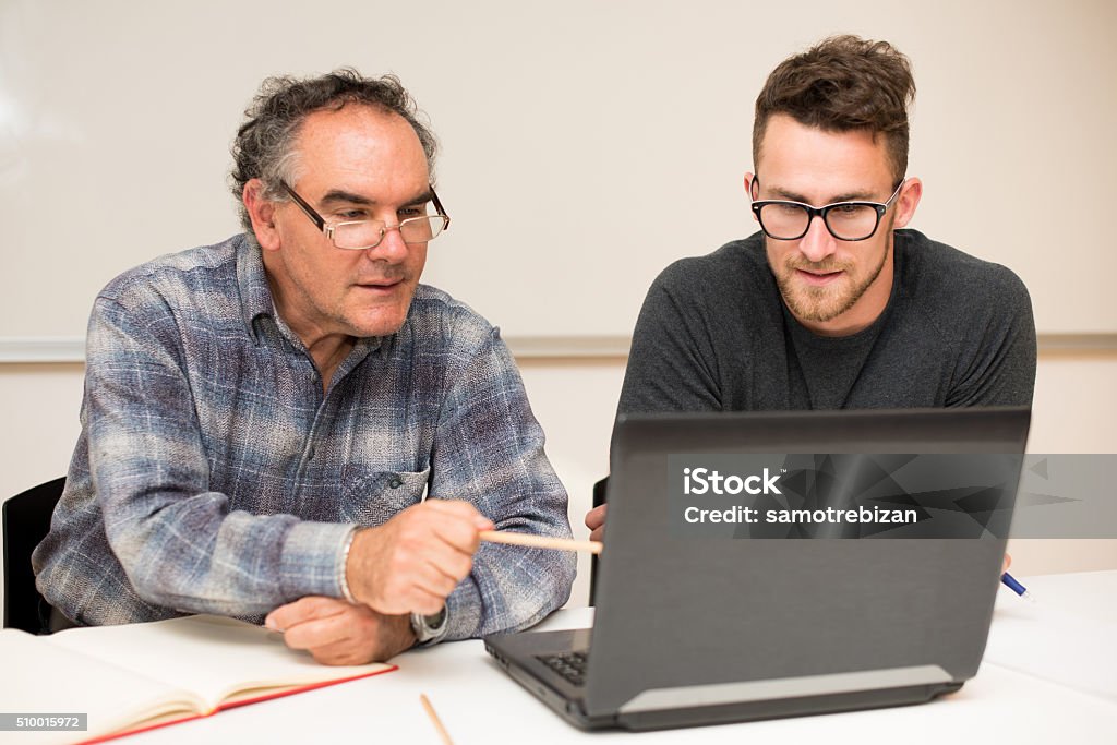 Giovane uomo insegnando anziani uomo di utilizzo del computer. - Foto stock royalty-free di Adulto