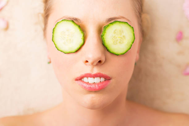 kobieta z twarzy maska z plasterki ogórka na oczy - cucumber human eye spa treatment health spa zdjęcia i obrazy z banku zdjęć