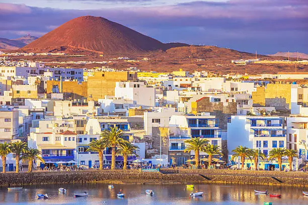 Fishing boats, houses and restaurants at the waterfront of Arrecife´s new harbour area, Charco de San Gines, at sunset.