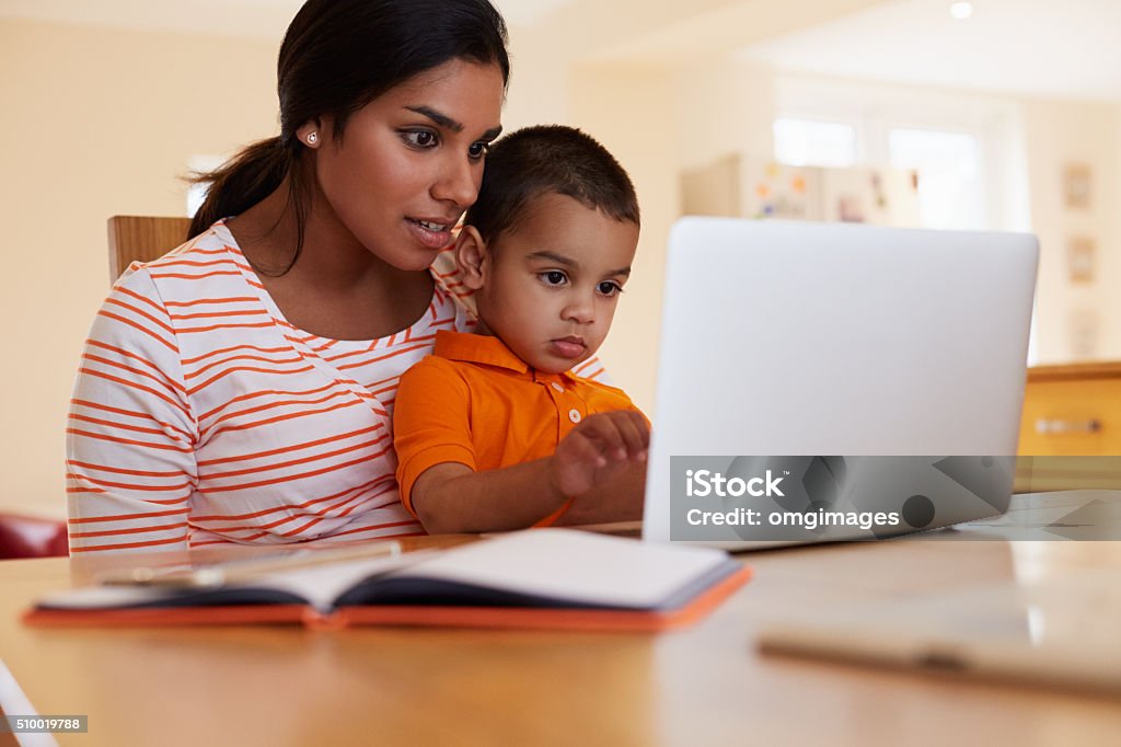 Mother And Son In Kitchen Looking At Laptop Together Child Stock Photo