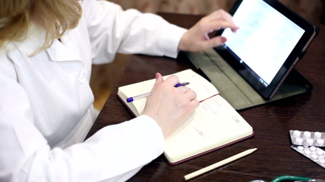 Doctor working with tablet computer and documents