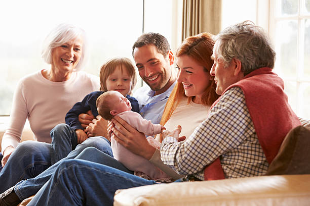 multi-generationen-familie sitzt auf sofa mit neugeborenen baby - familie mit mehreren generationen stock-fotos und bilder