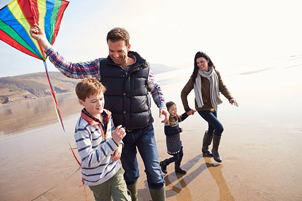 istock Family Running Along Winter Beach Flying Kite 510040819