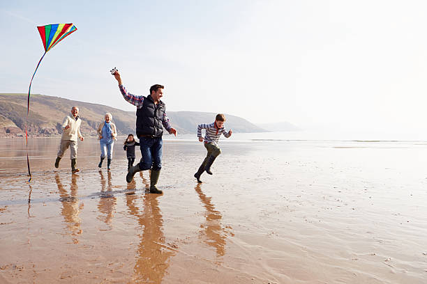Multi Generation Family Flying Kite On Winter Beach