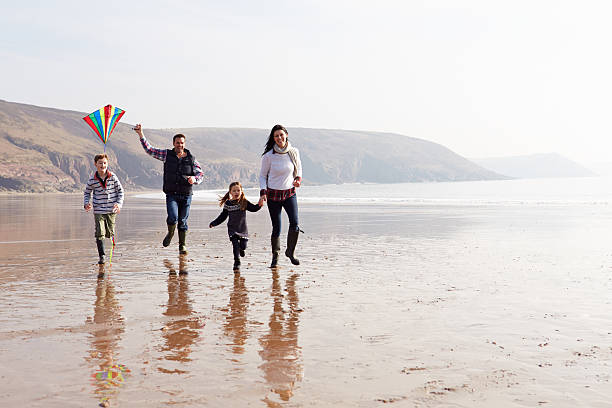 istock Family Running Along Winter Beach Flying Kite 510040849