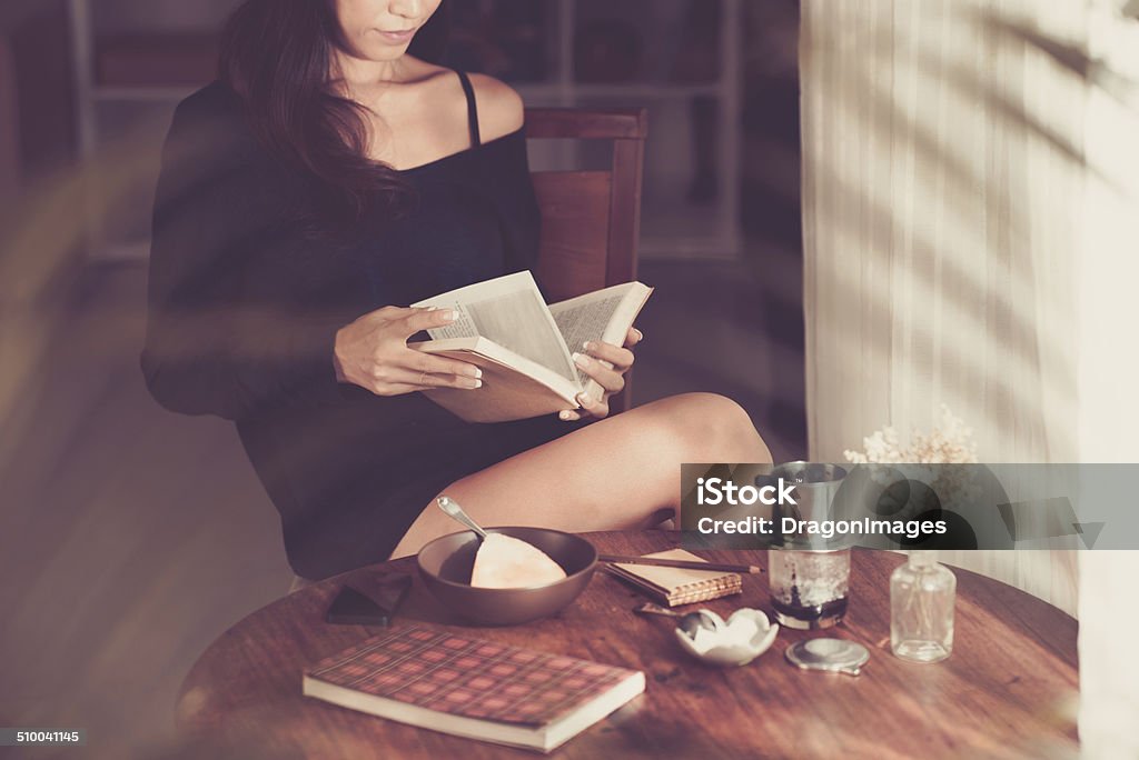 Reading a book Woman having breakfast and reading book at home Adult Stock Photo