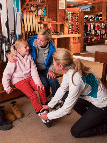 Mother and daughter try on snow boots in a ski shop preparing for the snow.