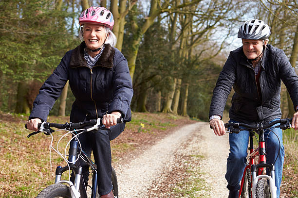 altes paar auf zyklus fahren im winter landschaft - couple senior adult travel action stock-fotos und bilder