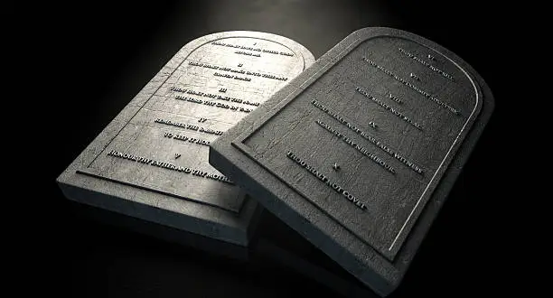 Two representative stone tablets with the ten commandments inscribed on them on an isolated dark ethereal background