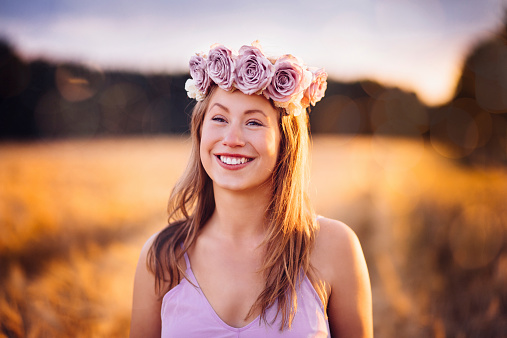 Girl with flower crown standing with wheat field background