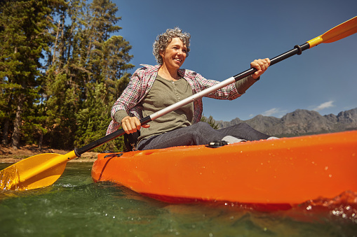 Portrait of senior woman paddling in a lake. Happy mature caucasian woman canoeing on summer day.