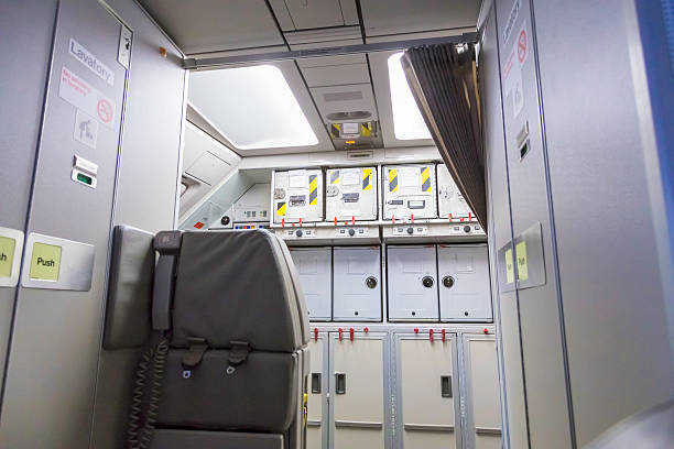 Food containers at the back inside a commercial aeroplane, with the lavatories seen on the left and right.