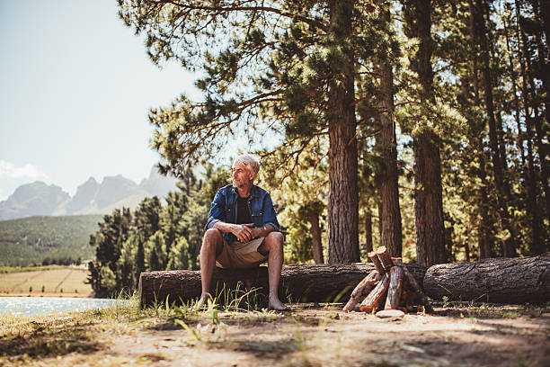 homem maduro relaxante em um lago - wood tranquil scene serene people lake imagens e fotografias de stock