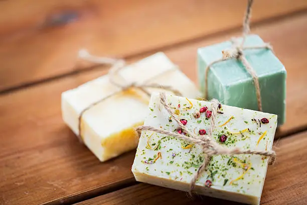 beauty, spa, body care, bath and natural cosmetics concept - close up of handmade soap bars on wooden table