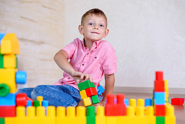 istock Cute cheeky young boy playing with building blocks 510068058