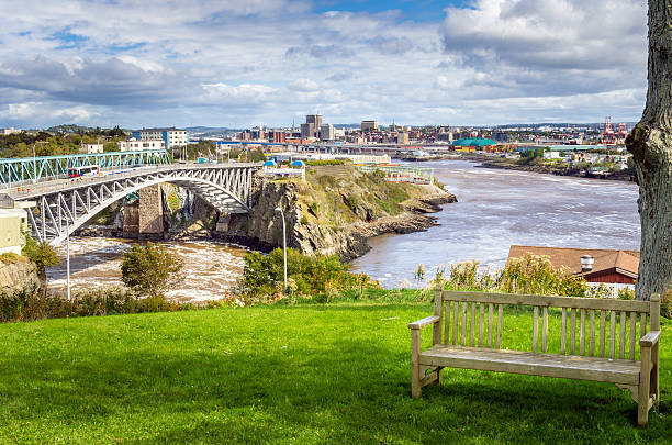 Saint John, New Brunswick Photo of Saint John, New Brunswick, from a park near the Reversing Falls Bridge. An empty wooden bench is in Foreground. new brunswick canada photos stock pictures, royalty-free photos & images