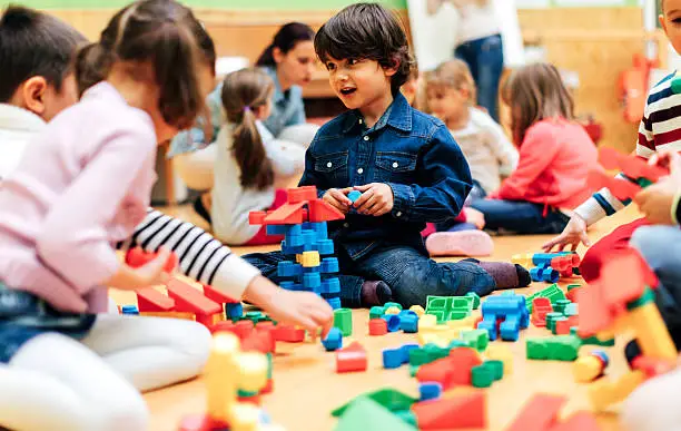 Photo of Group of children playing with blocks in kindergarten.