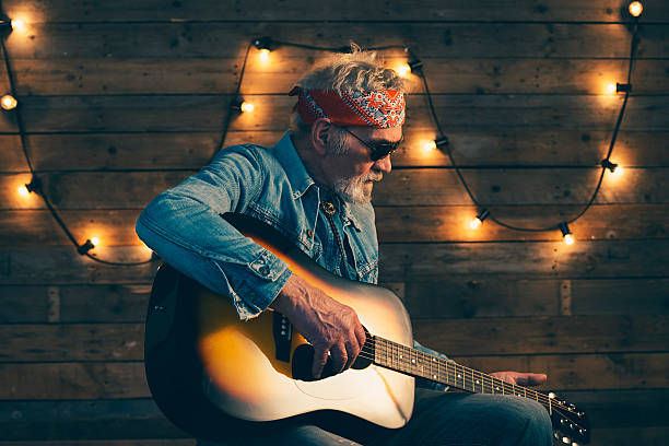 istock Senior guitarist with beard sitting on chair playing guitar. 510070392