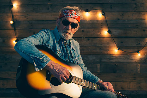 istock Senior guitarist with beard sitting on chair playing guitar. 510070420