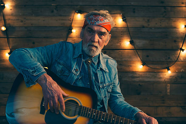 istock Senior guitarist with beard sitting on chair playing guitar. 510070522