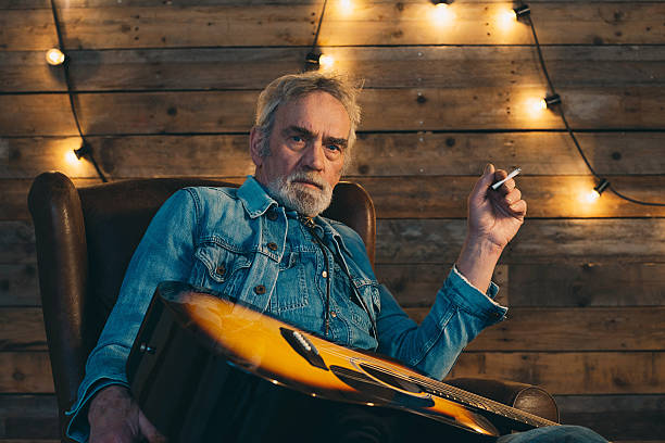 istock Smoking senior guitarist with beard sitting in chair. 510070836