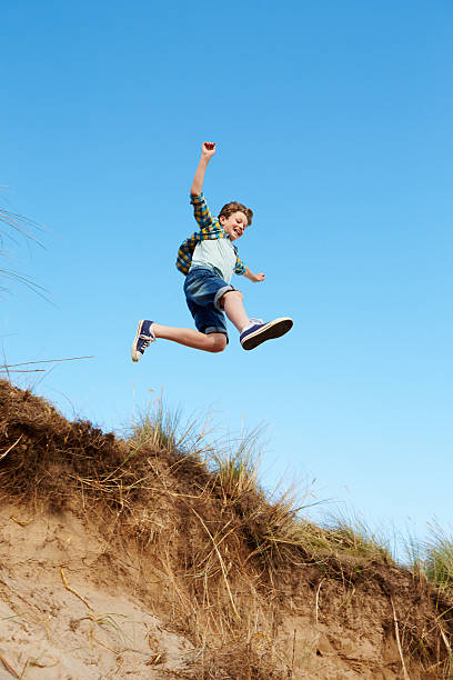 istock Action Shot Of Boy Jumping From Sand Dune 510072108