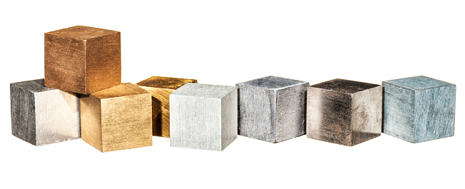 Metal cubes in a row, isolated on white. From left, tin,copper,brass,brass,aluminium,lead,iron and zinc.
