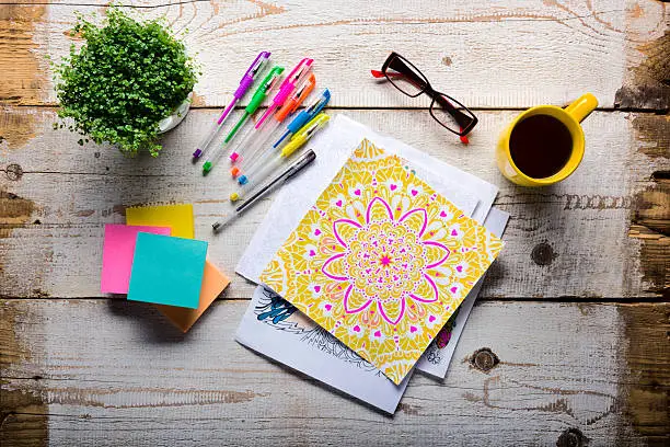 Photo of Retro desk with adult coloring books, stress relieving trend