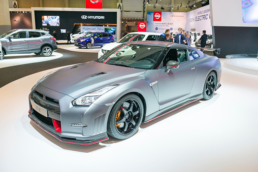 Brussels, Belgium - Januari 12, 2016: Gray Nissan GT-R Nismo sports car. The GT-R is equipped with a 3.8 L VR38DETT twin-turbo V6 producing 591 hp. The car is on display during the 2016 Brussels Motor Show. The car is displayed on a motor show stand, with lights reflecting off of the body. There are people looking around and other cars on display in the background.