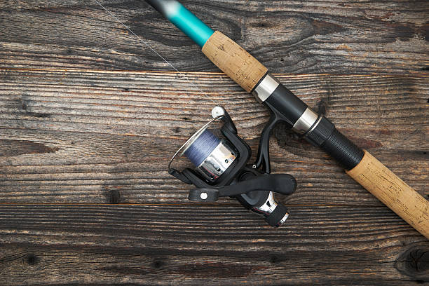 istock Fishing rod with reel, isolated on wooden background 510077372