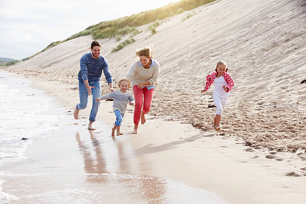 Family On Beach Vacation Running By Sea stock photo