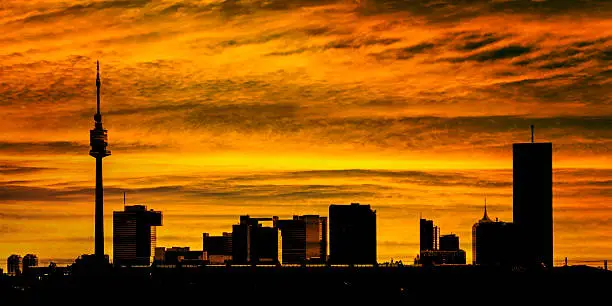 Panorama of Donau City skyline in Vienna, Austria with the famous UNO City and Donauturm Tower silhouette at sunset.