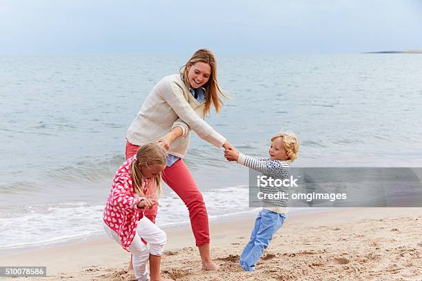 Mother And Children On Beach Vacation Playing By Sea Stock Photo - Download Image Now